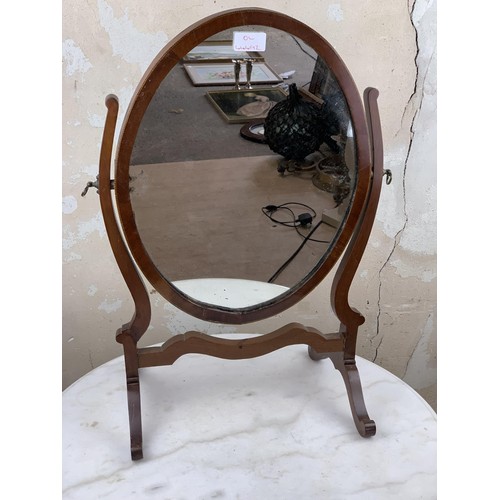 517 - AN OVAL INLAID DRESSING TABLE MIRROR IN A SHAPED FRAME