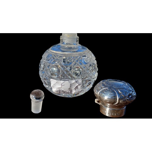 256 - AN ANTIQUE CUT GLASS PERFUME BOTTLE WITH STOPPER AND A BIRMINGHAM 1998 SILVER HEAVILY EMOBOSSED TOP