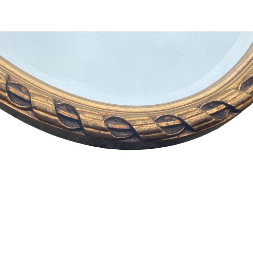 407 - AN ORNATE GILT OVAL BEVELLED EDGED MIRROR 24 x 14