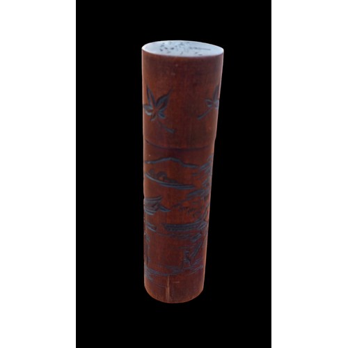 559 - A CARVED ORIENTAL WOODEN TUBE CONTAINING A WOODEN BOBBIN