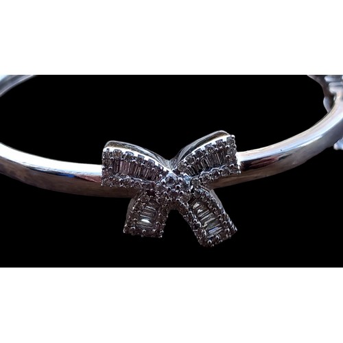 653 - A CHILDS 9ct WHITE GOLD BANGLE SET WITH DIAMONDS BOW TO CENTRE (BAGUETTE & BRILLIANT CUT DIAMONDS) P... 