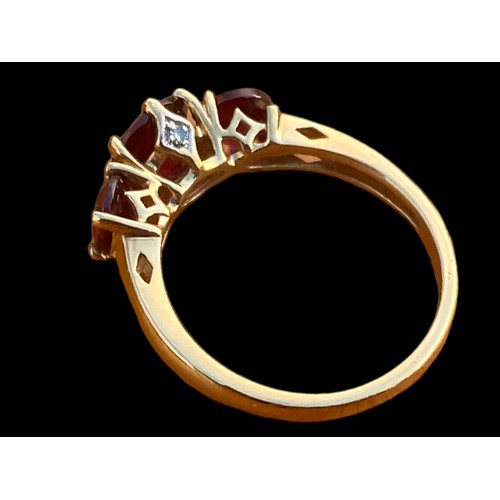 663 - A 9CT GOLD RING SET WITH 3 RUBY STYLE STONES WITH DIAMOND CHIPS TO THE OUTSIDE OF THE SETTING