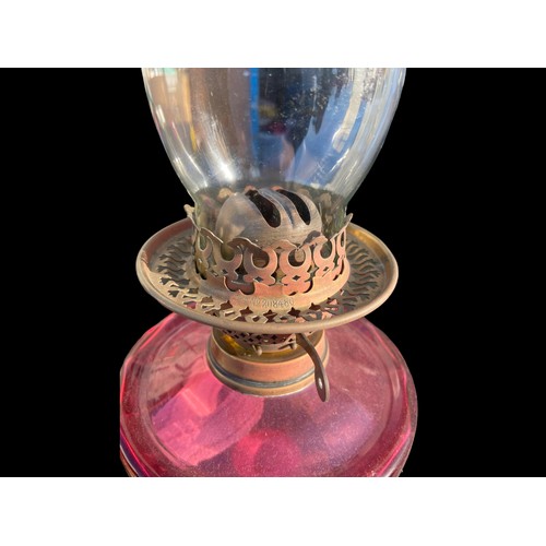 682 - A VICTORIAN ORNATE BRASS CORINTHIAN PILLARED OIL LAMP WITH A SHAPED RUBY BOWL COMPLETE WITH FUNNEL (... 