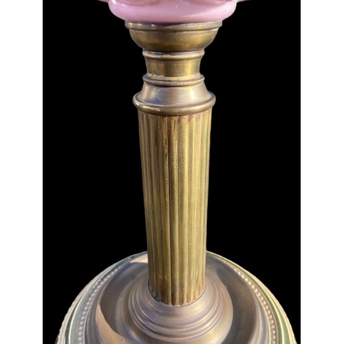 836 - A VICTORIAN ORNATE BRASS CORINTHIAN PILLARED OIL LAMP WITH A RUBY BOWL WITH A PORCELAIN BASE