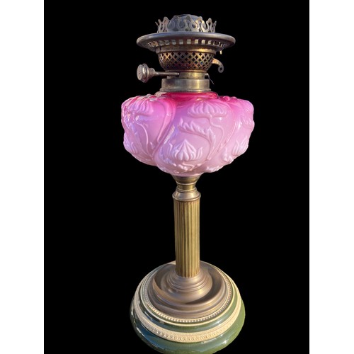 836 - A VICTORIAN ORNATE BRASS CORINTHIAN PILLARED OIL LAMP WITH A RUBY BOWL WITH A PORCELAIN BASE