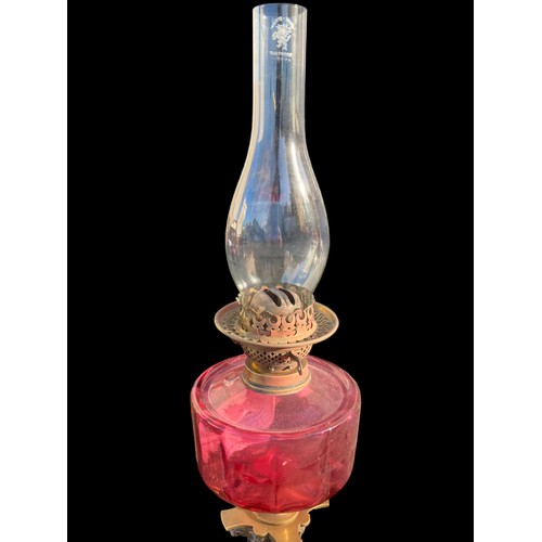 790 - A VICTORIAN ORNATE BRASS CORINTHIAN PILLARED OIL LAMP WITH A RUBY BOWL COMPLETE WITH FUNNEL