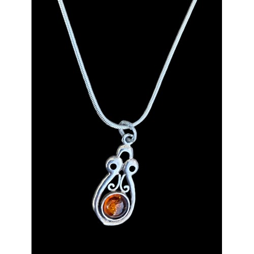 218 - AN ORNATE AMBER PENDANT ON A SILVER SNAKE CHAIN