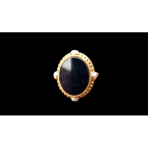 553 - A LARGE OVAL BLACK STONE RING 4 PEARLS TO THE OUTER MOUNT & BLACK STONES TO SHOULDER