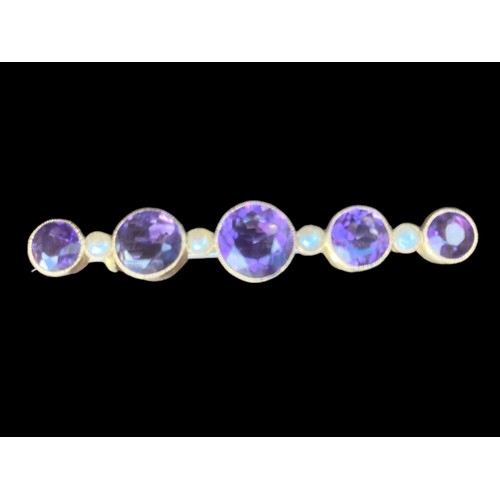 517 - A BROOCH SET WITH 5 GRADUATED ROUND AMETHYST 4.5cm IN LENGTH AND 5 SEED PEARLS IN YELLOW RUBOVER SET... 