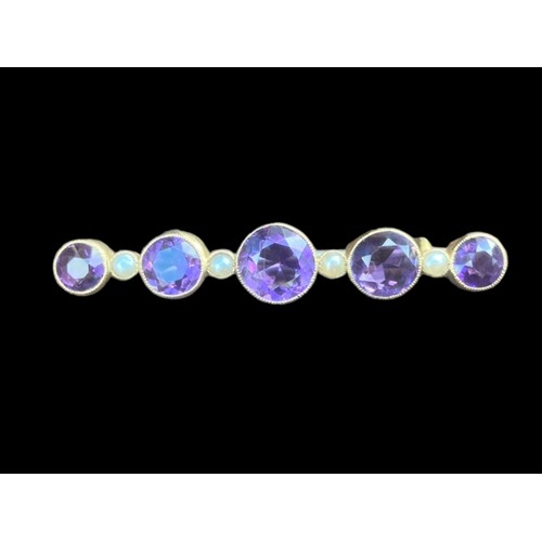 517 - A BROOCH SET WITH 5 GRADUATED ROUND AMETHYST 4.5cm IN LENGTH AND 5 SEED PEARLS IN YELLOW RUBOVER SET... 