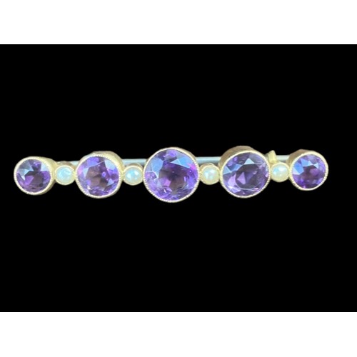 517 - A BROOCH SET WITH 5 GRADUATED ROUND AMETHYST 4.5cm IN LENGTH AND 5 SEED PEARLS IN YELLOW RUBOVER SET... 