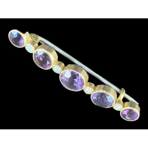 517 - A BROOCH SET WITH 5 GRADUATED ROUND AMETHYST 4.5cm IN LENGTH AND 5 SEED PEARLS IN YELLOW RUBOVER SET... 