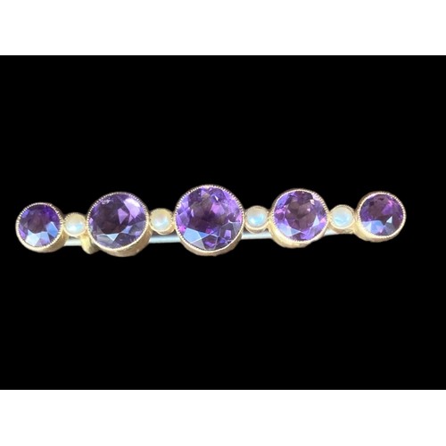 517 - A BROOCH SET WITH 5 GRADUATED ROUND AMETHYST 4.5cm IN LENGTH AND 5 SEED PEARLS IN YELLOW RUBOVER SET... 