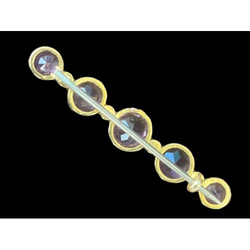 517 - A BROOCH SET WITH 5 GRADUATED ROUND AMETHYST 4.5cm IN LENGTH AND 5 SEED PEARLS IN YELLOW RUBOVER SET... 