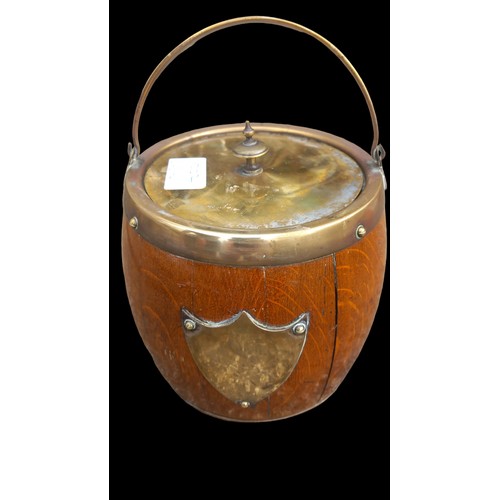 142 - AN ANTIQUE OAK BISCUIT BARREL WITH BRASS TRIM WITH A PORCELAIN LINER