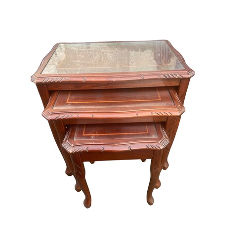 57 - A NEST OF GLASS TOPPED MAHOGANY TABLES