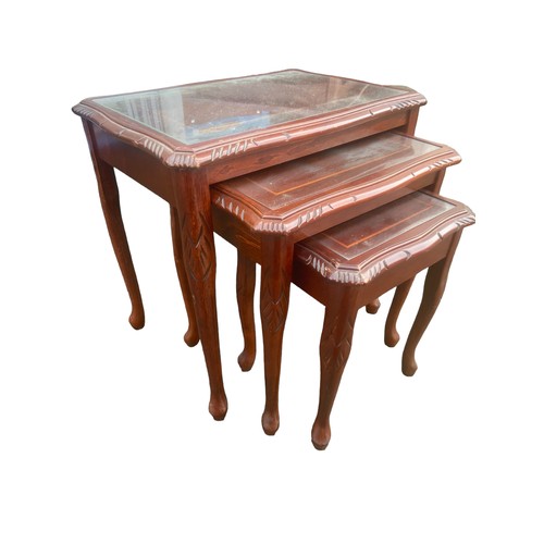 57 - A NEST OF GLASS TOPPED MAHOGANY TABLES