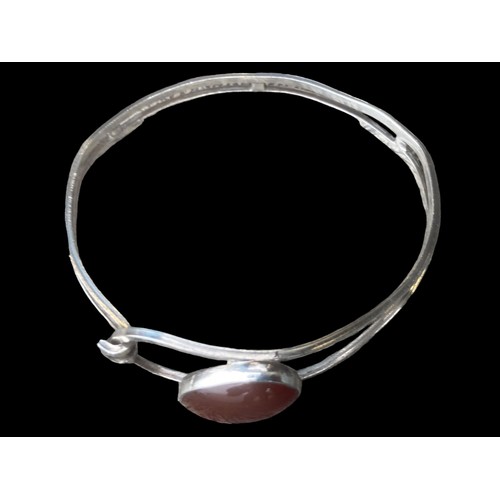 494 - AN ORNATE SILVER BANGLE SET WITH A CORNELIAN STYLE STONE