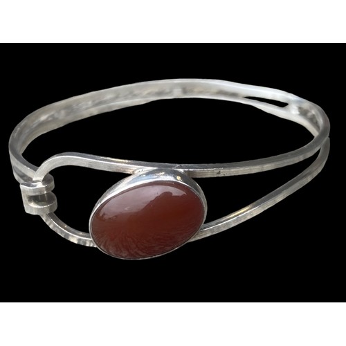 494 - AN ORNATE SILVER BANGLE SET WITH A CORNELIAN STYLE STONE