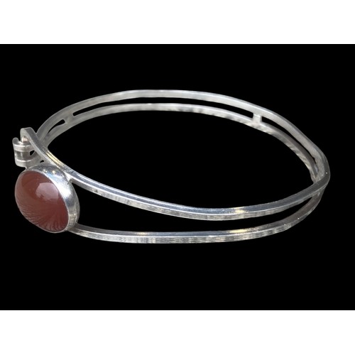 494 - AN ORNATE SILVER BANGLE SET WITH A CORNELIAN STYLE STONE