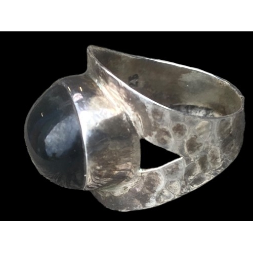 507 - A SILVER DESIGNER STYLE RING SET WITH AN UNUSAL BLACK STONE (BEATEN SILVER DESIGN)