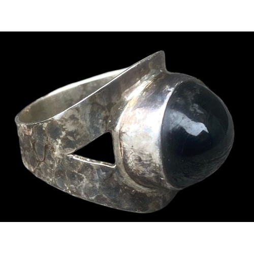 507 - A SILVER DESIGNER STYLE RING SET WITH AN UNUSAL BLACK STONE (BEATEN SILVER DESIGN)