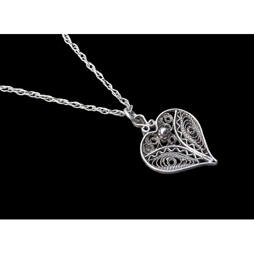 521 - A SILVER FILAGREE HEART PENDANT ON A SILVER CHAIN