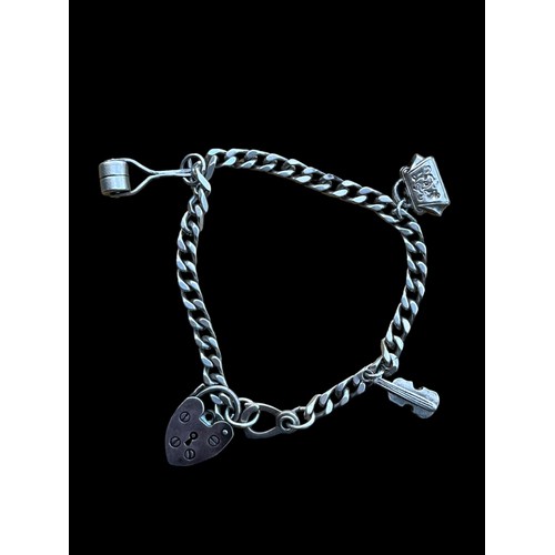 502 - A SILVER FLANTLINK BRACELET WITH SILVER HEART SHAPED LOCK AND SOME CHARMS