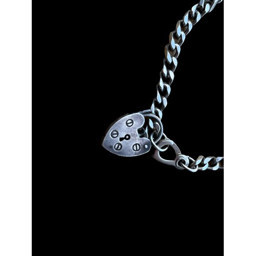 502 - A SILVER FLANTLINK BRACELET WITH SILVER HEART SHAPED LOCK AND SOME CHARMS