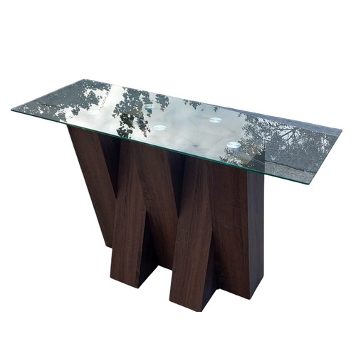 131 - A DESIGNER WALNUT CROSSED FRAMED CONSOL TABLE WITH A GLASS TOP