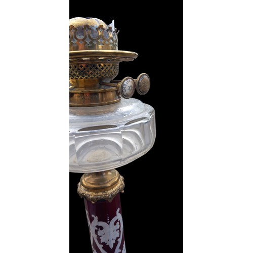 563 - A VICTORIAN HAND PAINTED RUBY GLASS PILLARED OIL LAMP WITH CLEAR GLASS BOWL DOUBL HINKS BURNER ON A ... 