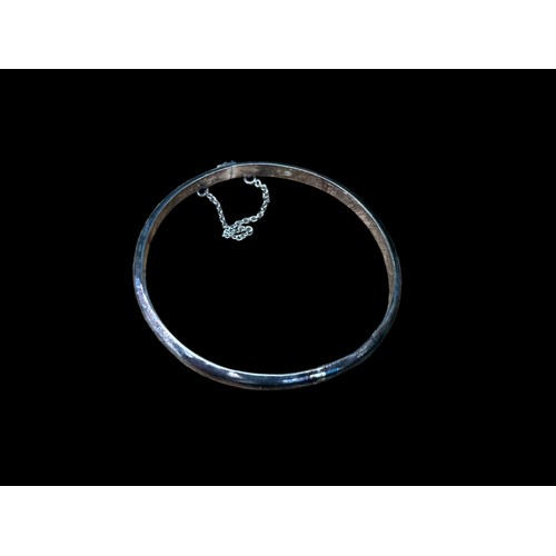 217 - A SILVER CURVED BANGLE WITH SAFETY CHAIN