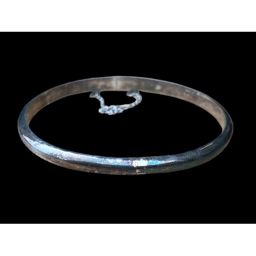 217 - A SILVER CURVED BANGLE WITH SAFETY CHAIN