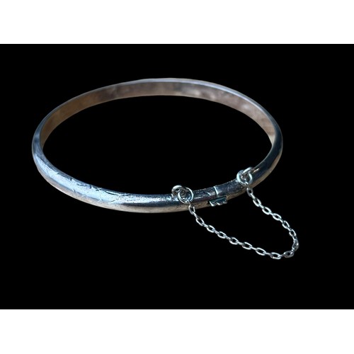 246 - A SILVER FLORAL DESIGN BANGLE WITH SAFETY CATCH