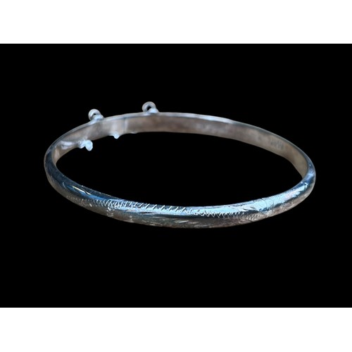 476 - AN ORNATELY DESIGNED SILVER BANGLE WITH SAFETY CATCH