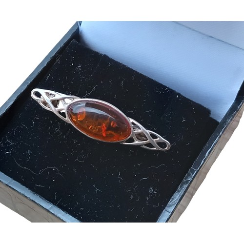 685 - A SILVER CELTIC DESIGNED BROOCH SET WITH AMBER STONE