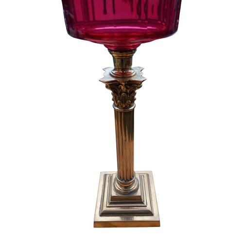 786 - A STUNNING SHAPED DARK RUBY BOWL OIL LAMP ON AN ORNATE BRASS PILLARED BASE COMPLETE WITH FUNNEL