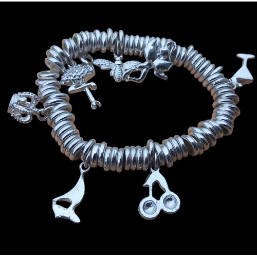 612 - A LOT OF 3 BRACELETS A SILVER EXPANDING WITH 7 CHARMS , ASILVER OPEN CIRCLE BANGLE AND A WHITE METAL... 