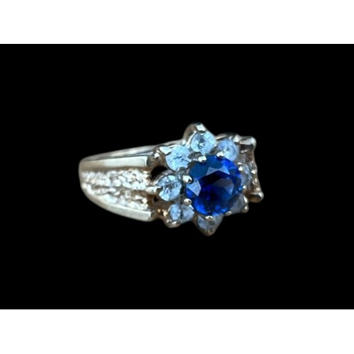 642 - A 9CT GOLD CLUSTER RING WITH A BLUE CENTRE STONE SURROUNDED BY 8 CLEAR STONES WEIGH 3.7G