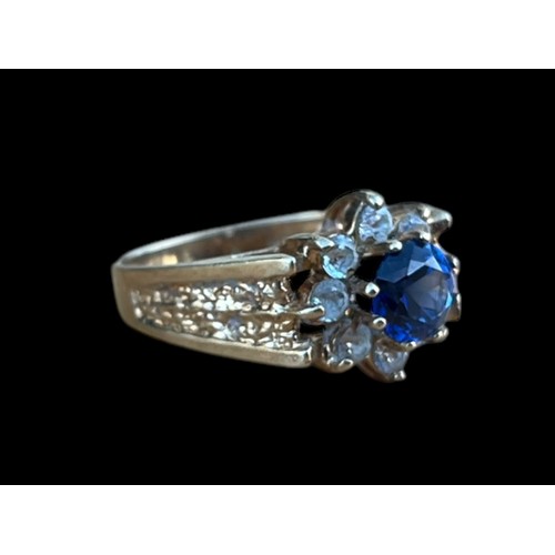 642 - A 9CT GOLD CLUSTER RING WITH A BLUE CENTRE STONE SURROUNDED BY 8 CLEAR STONES WEIGH 3.7G