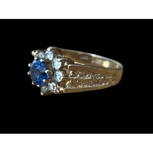 642 - A 9CT GOLD CLUSTER RING WITH A BLUE CENTRE STONE SURROUNDED BY 8 CLEAR STONES WEIGH 3.7G