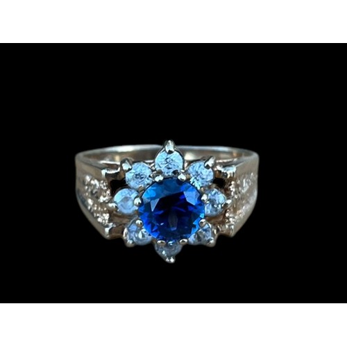 642 - A 9CT GOLD CLUSTER RING WITH A BLUE CENTRE STONE SURROUNDED BY 8 CLEAR STONES WEIGH 3.7G