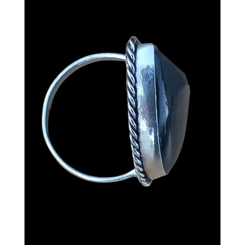 210 - AN ORNATE SILVER RING SET WITH A BLACK STONE