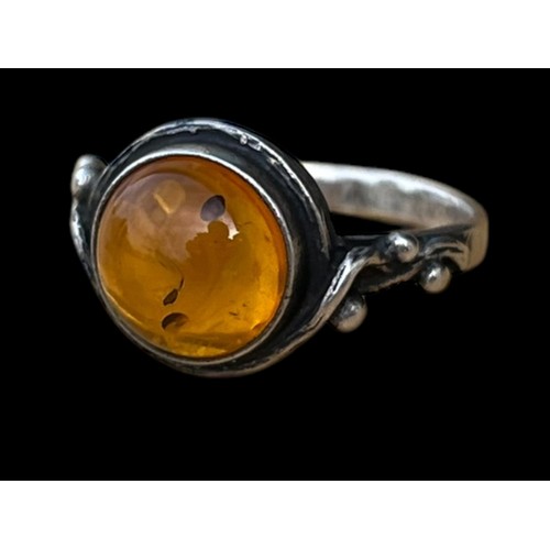 453 - AN ORNATE SILVER RING SET WITH A GENEROUS AMBER STONE