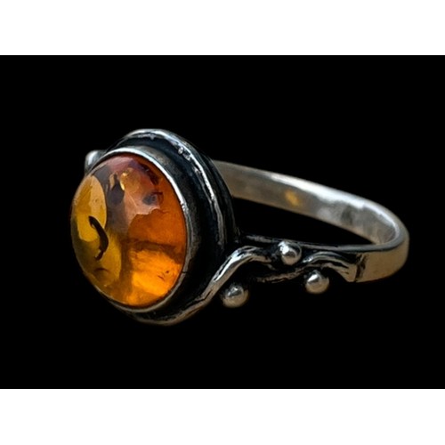 453 - AN ORNATE SILVER RING SET WITH A GENEROUS AMBER STONE