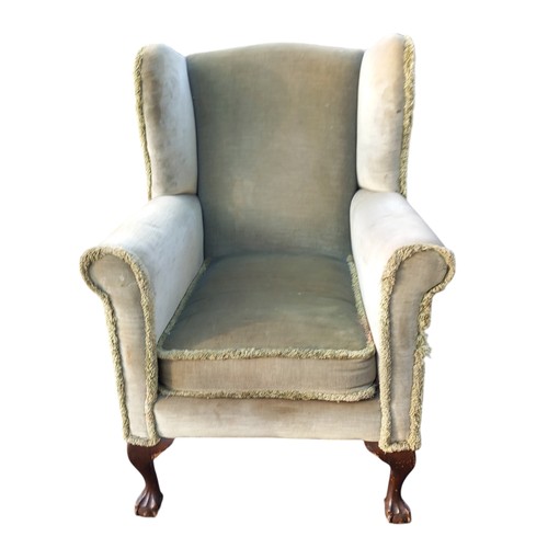 594 - AN ANTIQUE WINGBACK ARMCHAIR ON BALL AND CLAW FOOT