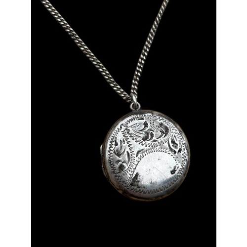 259 - AN ORNATE CIRCULAR SILVER LOCKET ON A SILVER CHAIN