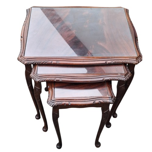 83 - A GLASS TOPPED NEST OF THREE MAHOGANY NEST OF TABLES