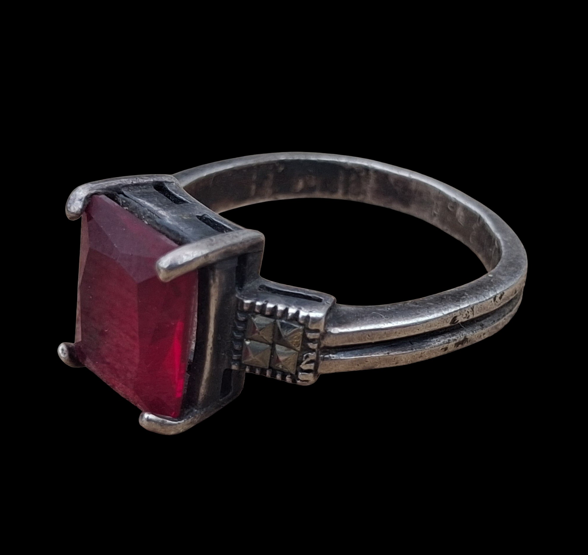 A SILVER MARCASITE RING SET WITH A RED STONE