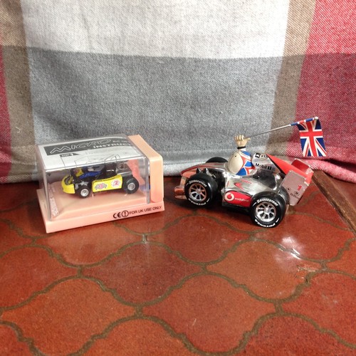 116 - Two Micro Collectables. Refer Description. 
1. Lewis Hamilton. Designed by Cartoonist, Jim Bamber, c... 